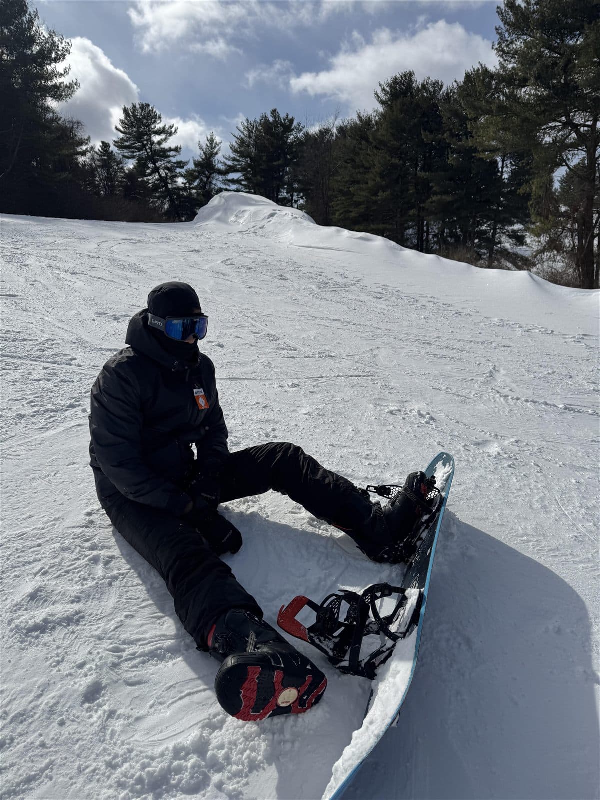 Sitting on a snowy slope with a snowboard strapped in